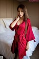 A woman in a red robe standing on a bed.