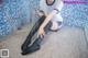 A woman sitting on the floor in a bathroom with a shower head.