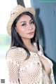 A woman wearing a straw hat leaning against a wall.