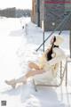 A woman sitting on a bench in the snow.