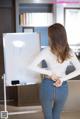 A woman standing in front of a white board with writing on it.