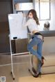 A woman standing next to a white board with writing on it.