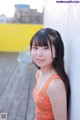 A young girl leaning against a white wall.