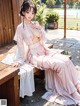 A woman in a pink kimono sitting on a wooden bench.