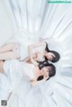 A couple of women laying on top of a bed.