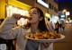 A woman holding a plate of food on a city street.