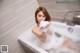 A woman taking a bath in a bathtub with foam.