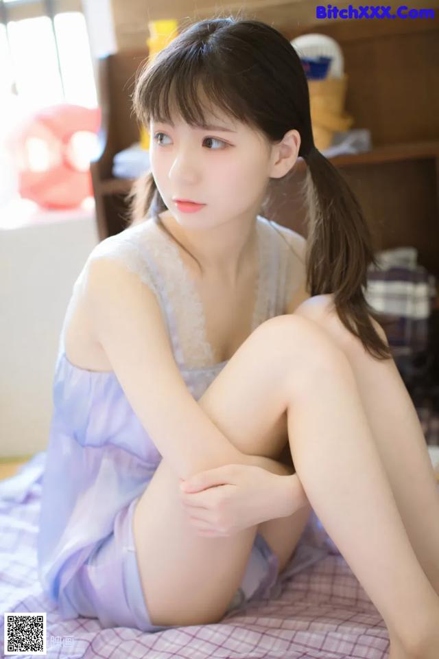 A woman sitting on top of a bed in a blue dress.