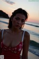 A woman in a red bathing suit standing on a beach.