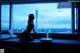 A woman sitting on a couch in front of a window.