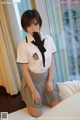 A woman in a school uniform sitting on a bed.