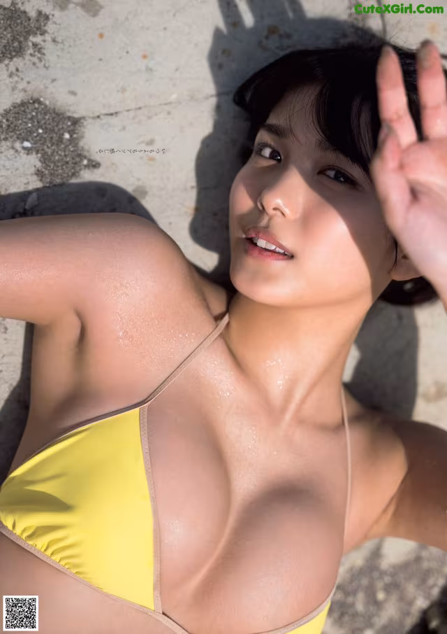 A woman in a yellow bikini laying on the ground.