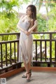 A woman in a silver dress standing on a balcony.