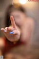 A woman with a blue manicure is making a peace sign.