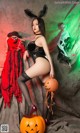 A woman in a black lingerie posing next to a pumpkin.