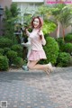 A woman in a pink and white striped shirt and skirt jumping in the air.