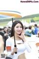 A woman holding an umbrella in front of a crowd.