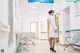 A woman in a white lab coat standing in a hospital hallway.