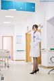 A woman in a white lab coat standing in a hospital hallway.