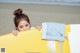 A young girl holding a yellow surfboard on the beach.